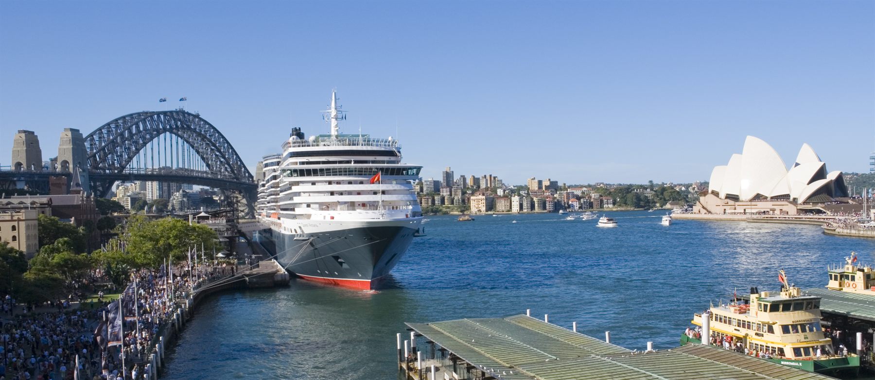 A cruise ship docked at Circular Quay beside the Sydney Harbour Bridge, with the Opera House across the water