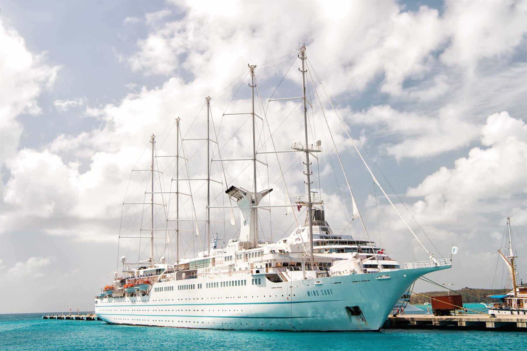 The five-masted sail cruise ship Wind Surf docked beside turquoise water